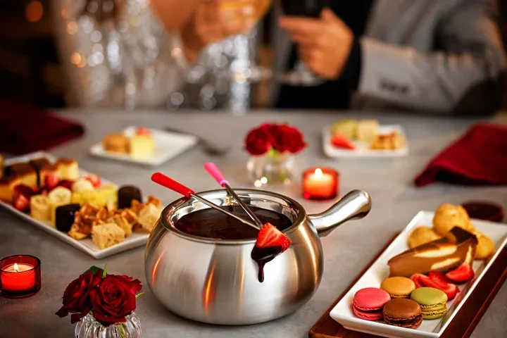 Silver chocolate fondue pot, dipped strawberry, dippables, roses, and candles.