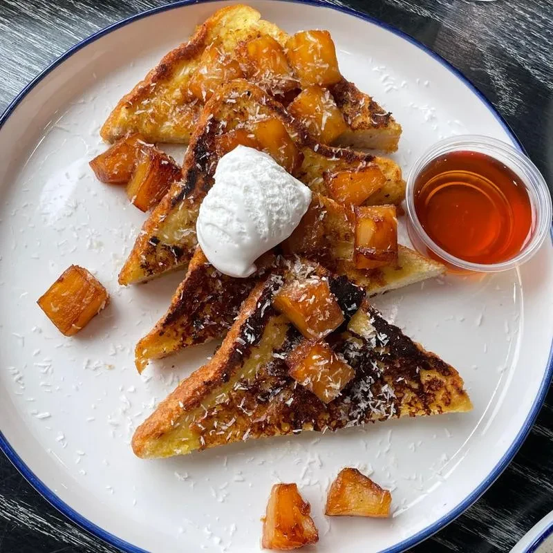 Top-down: French toast, fruit, coconut, cream, syrup.
