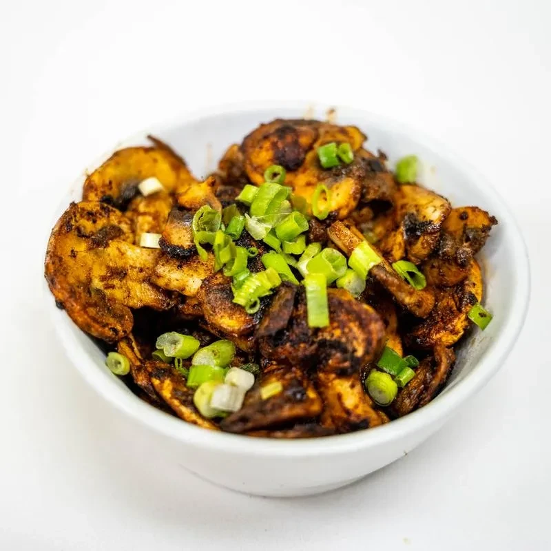 White bowl of caramelized mushrooms, garnished with green onions.