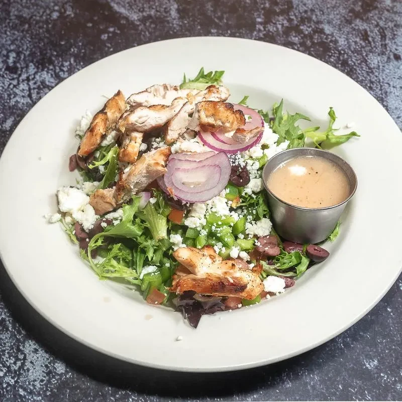 Grilled chicken salad with feta, red onion, olives, peppers, and dressing.
