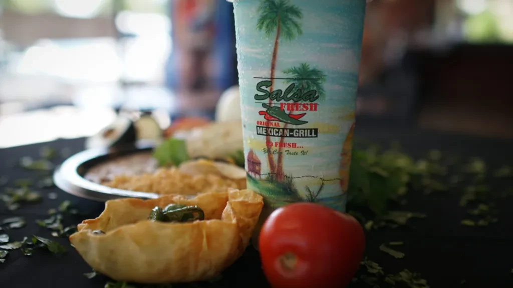 Mexican meal with peppers, tomato, rice, beans, and branded beverage.