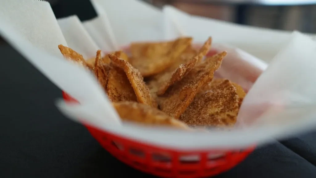 Crispy, golden-brown cinnamon sugar fried pastries in a paper-lined red basket.