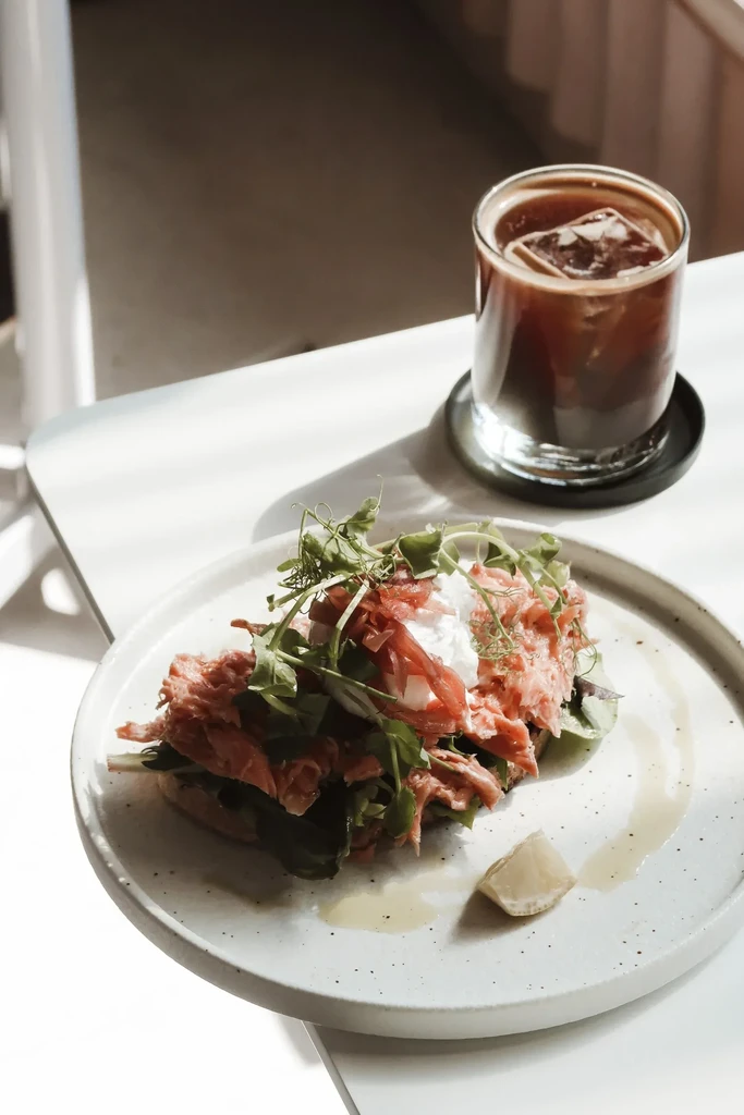 Flaked salmon meal with microgreens, lemon, and an iced drink.