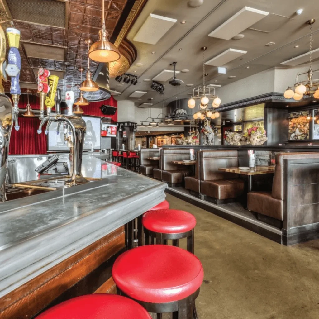 Inviting bar interior with red stools, copper ceiling, and leather booths.