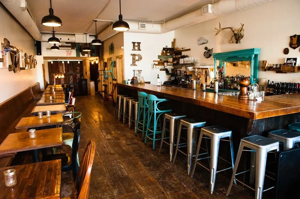 Empty rustic bar interior with wooden tables and a long bar.