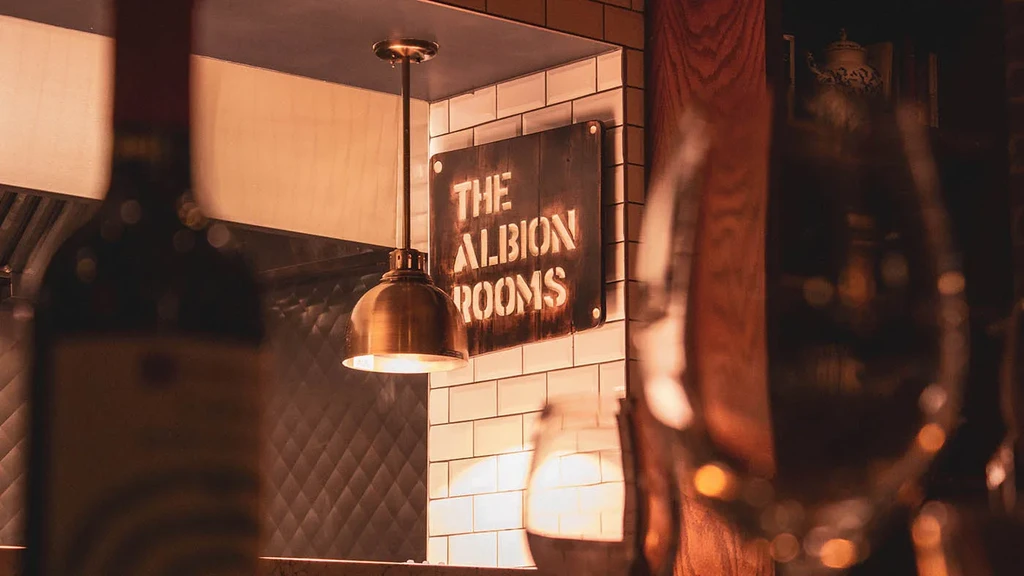 Stenciled 'THE ALBION ROOMS' sign illuminated by a bronze pendant lamp.