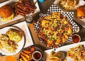 Overhead view of a large brunch spread with burgers, nachos, and pancakes.