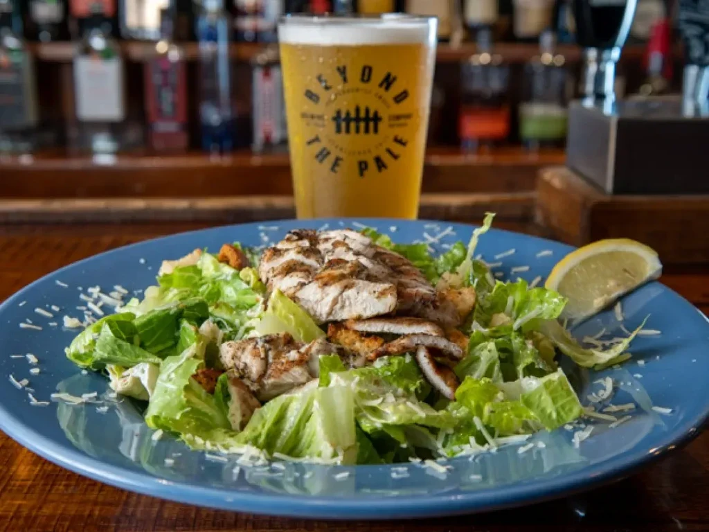 Caesar salad with grilled chicken, lemon, and Beyond the Pale beer.