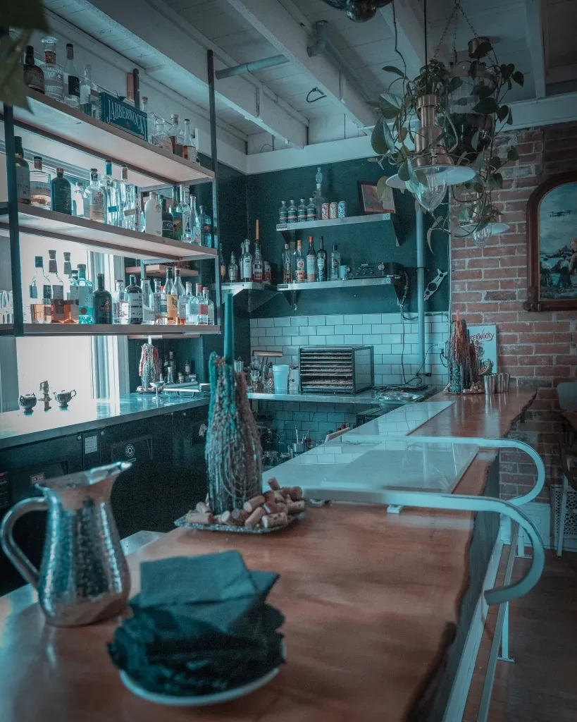 Well-stocked bar interior with many liquor bottles and a wooden counter.