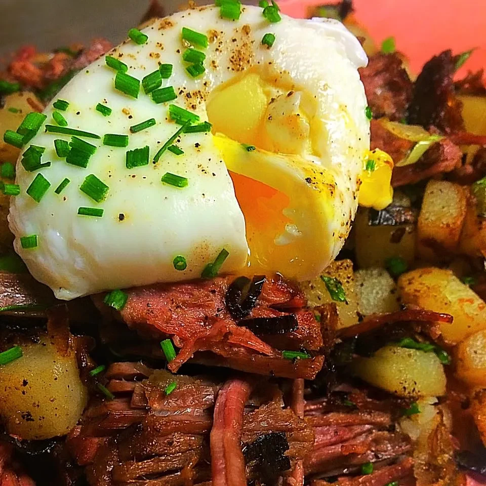 Runny poached egg, shredded meat, and crispy potatoes topped with chives.