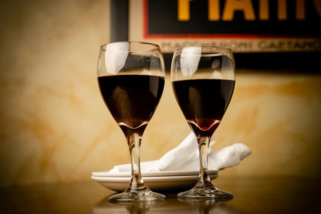 Two elegant red wine glasses in a warm restaurant setting.