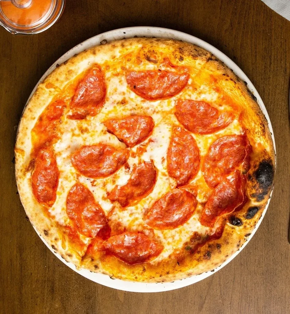 Whole pepperoni pizza with melted cheese, crispy pepperoni, charred crust.