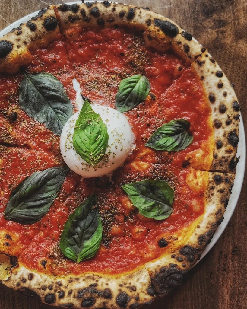 Freshly baked Neapolitan pizza with burrata, basil, and tomato sauce.