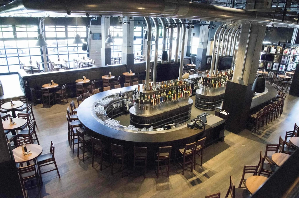 Modern, empty restaurant interior with a large, curved, well-stocked bar.