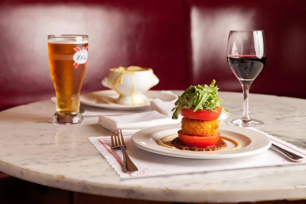 Restaurant table with tomato stack, cheese gratin, beer, and wine.