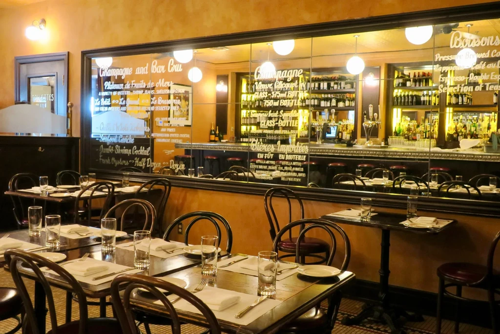 Empty restaurant interior with tables, chairs, and a mirrored bar menu.