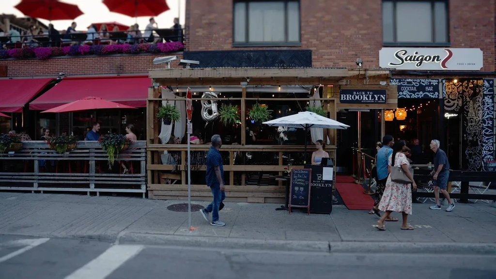 Lively street scene with restaurants, outdoor dining, and people at evening.