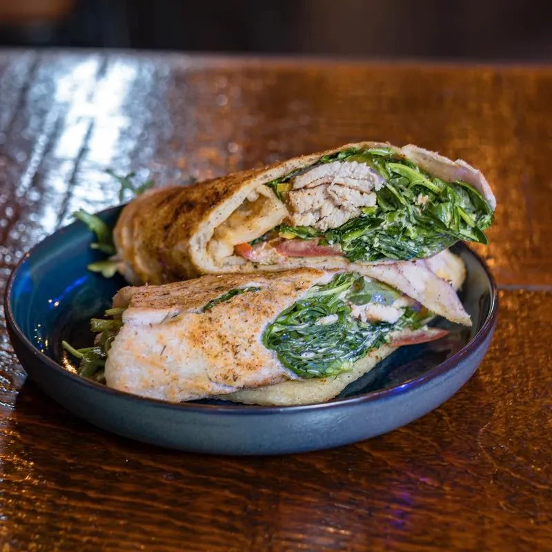 A sliced chicken and vegetable wrap on a dark blue plate.