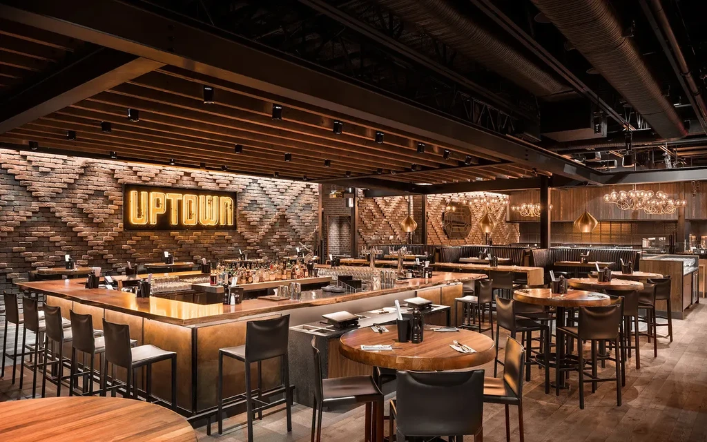 Stylish restaurant bar with a U-shaped bar and glowing "UPTOWN" sign.