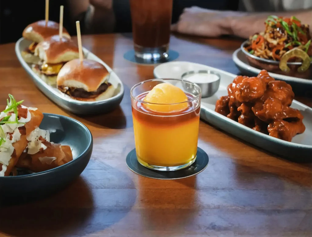 Warmly lit restaurant table filled with diverse appetizers and drinks.