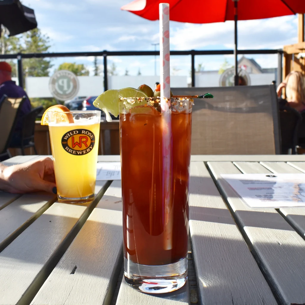 Bloody Mary and Wild Rose beer on a sunny outdoor patio table.