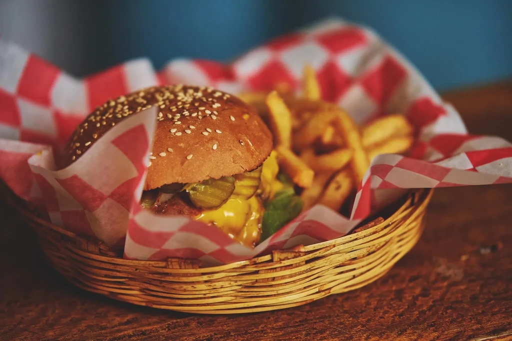 Cheeseburger with melted cheese and crispy fries in a wicker basket.