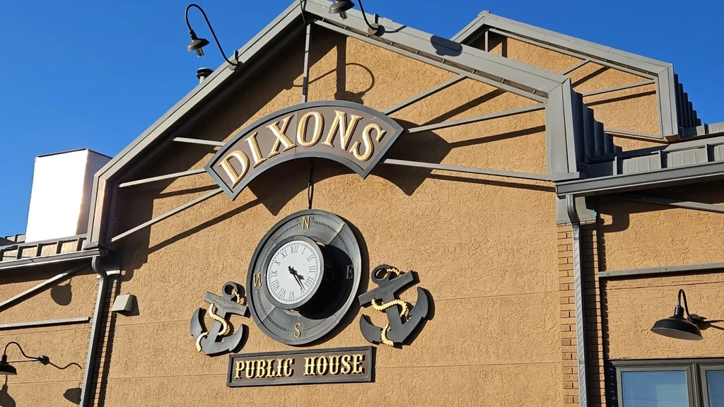 DIXONS PUBLIC HOUSE sign on building facade with clock, anchors.