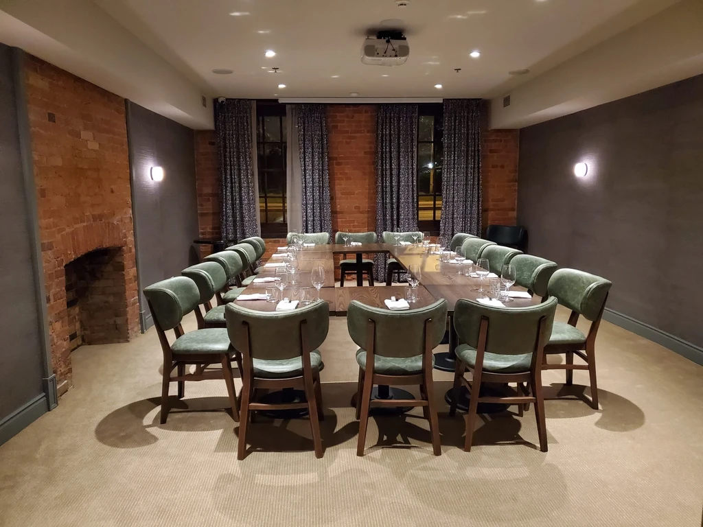 Private dining room with U-shaped table, green chairs, fireplace, projector.