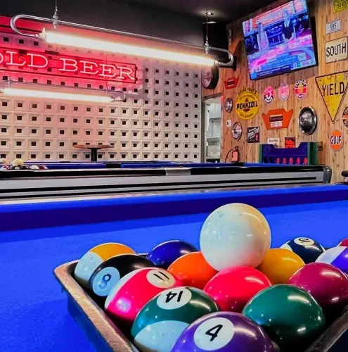 Blue pool table with racked balls, a neon sign, and vintage decor.