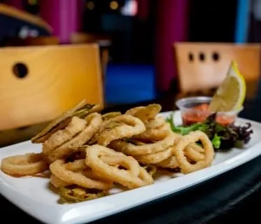 Crispy fried calamari with peppers, dipping sauce, and lemon.