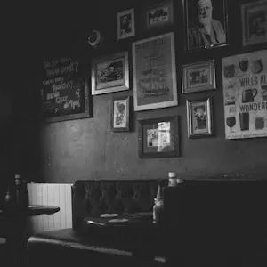 Black and white vintage pub interior with booth and framed art.