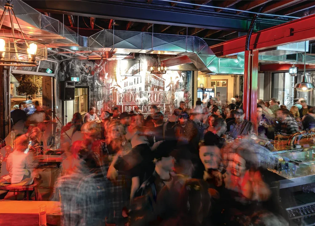Ridge Rock Brewing's bustling interior with motion-blurred people and industrial decor.
