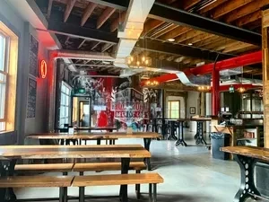 Industrial-chic restaurant interior with exposed beams, wooden tables, and red accents.