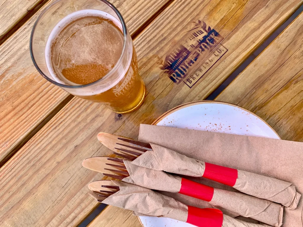 Golden beer, wrapped cutlery, and "Ridge Rock Brewing Co." logo on table.