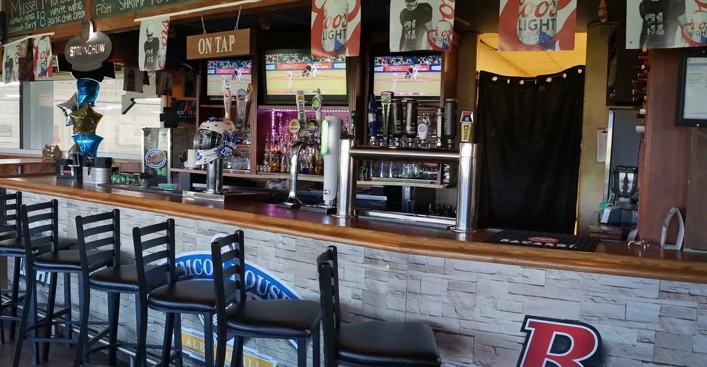 Empty sports bar: long wooden bar, TVs showing baseball, beer taps.