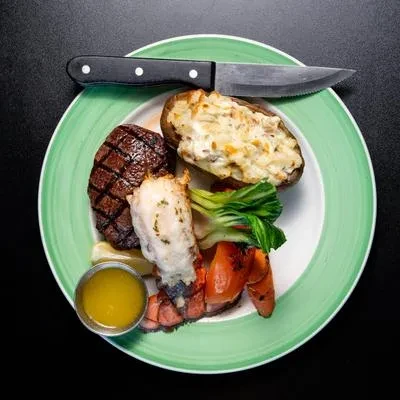 Top-down view of a steak, lobster, potato, and bok choy meal.