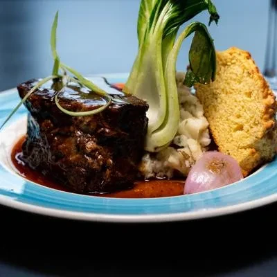 Plate of braised short ribs, mashed potatoes, cornbread, and bok choy.