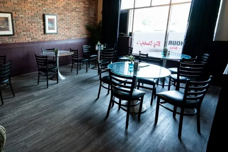 Restaurant interior: round tables, brick wall, art, and 'Big Daddy's' window sign.