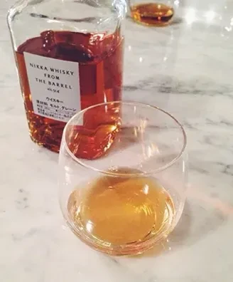 Nikka From The Barrel whisky bottle behind a glass with amber liquid.
