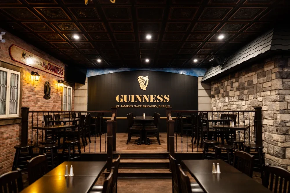 Rustic, multi-level Irish pub interior with empty dark wood seating and Guinness.