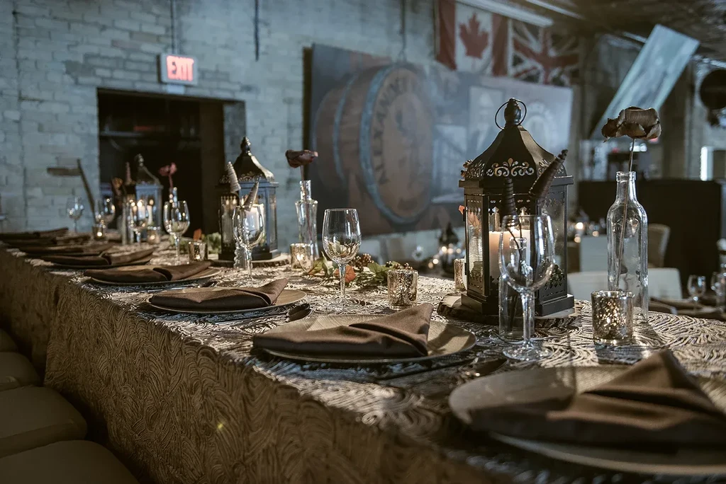 Long dining table with candlelit lanterns, dark flowers, and international flags.