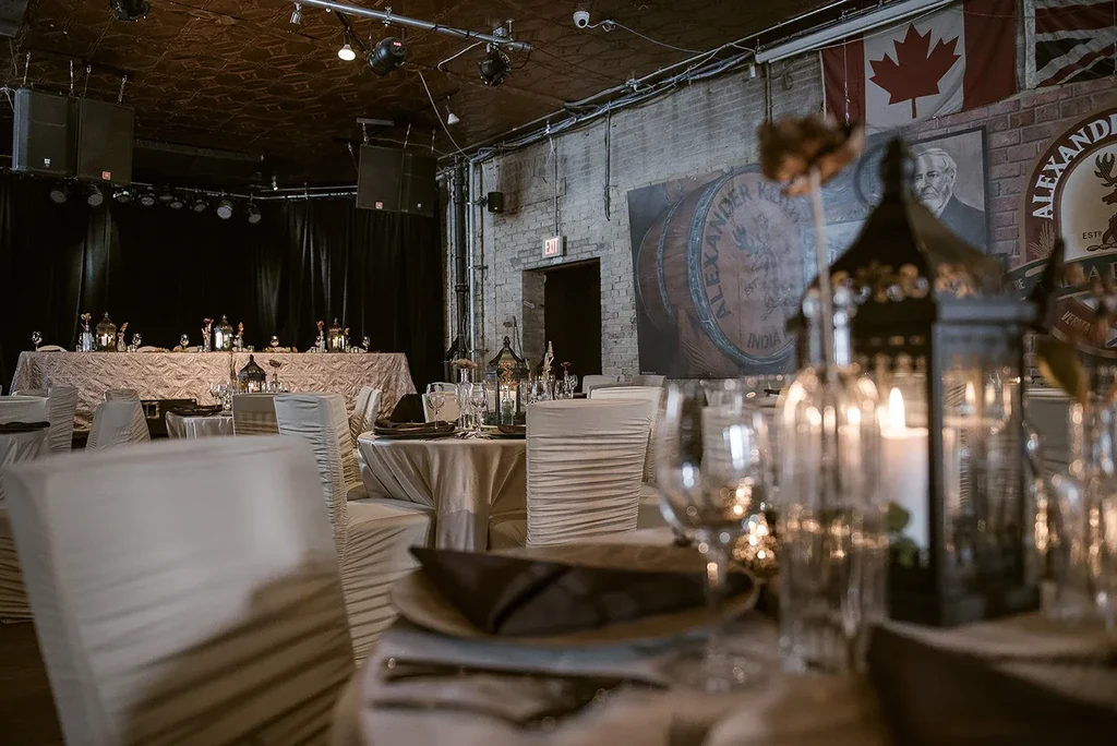 Elegantly set banquet hall with stage, brick wall, and brewery decor.