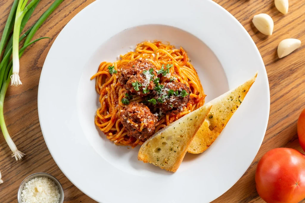 Spaghetti and meatballs with garlic bread, Parmesan, and parsley.