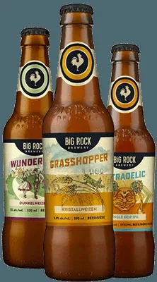 Three staggered amber Big Rock Brewery beer bottles with distinct labels.