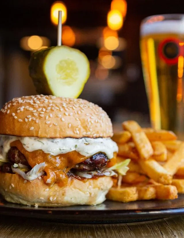Close-up of a gourmet burger, thick-cut golden fries, and beer.