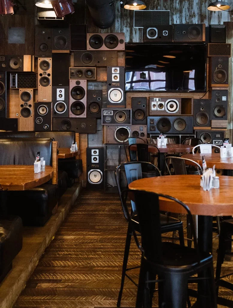Wall covered in audio speakers dominates rustic restaurant interior.