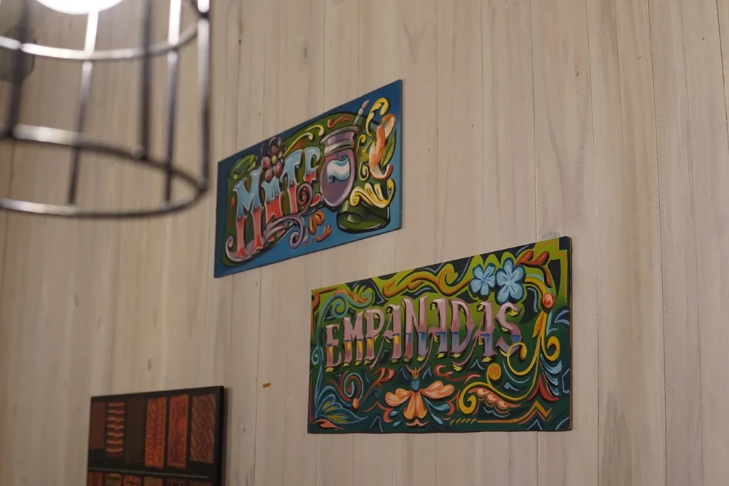 Colorful floral Empanadas and Mate signs on wooden wall.