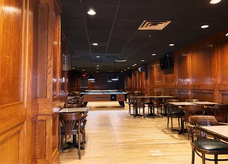 Long, wood-paneled bar interior with a pool table and seating.