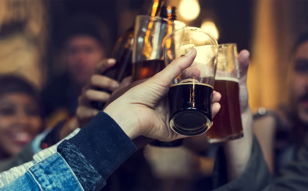 Hands toast with different beers, from dark stout to amber ale.
