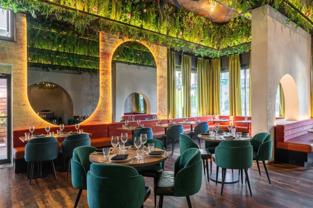 Empty restaurant dining room with botanical ceiling and arched alcoves.